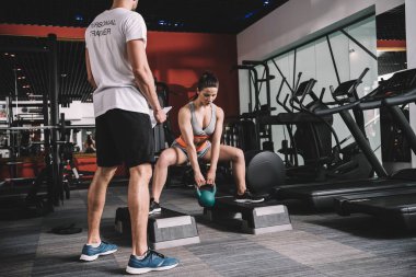 Spor salonundaki ağırlık kaldıran spor kadınlarını denetleyen özel antrenör görüşü