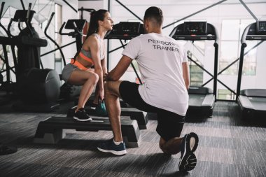 Spor eğitmeninin spor salonundaki ağırlık kaldıran genç bayana arka planı
