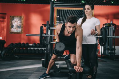 Çekici antrenör yakışıklı sporcuya yardımcı oluyor.