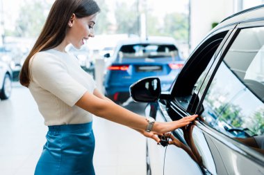 side view of excited young woman looking at black car 