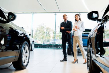 selective focus of man and woman walking in car showroom 