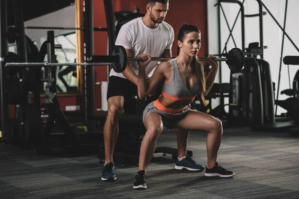 Attentive Handsome Trainer Supporting Young Attractive Sportswoman Lifting Barbell — Stock Photo, Image