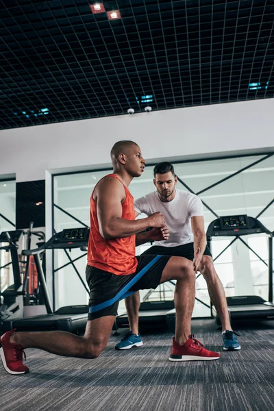 Attentive Trainer Controlling African American Sportsman Exercising Resistance Band — Stock Photo, Image