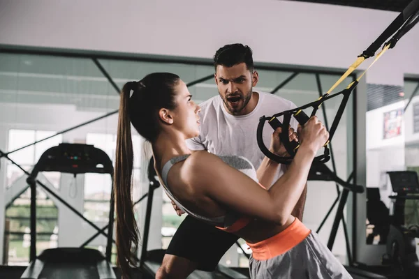 Cropped View Trainer Supporting Young Sportswoman Pulling Suspension Trainer — Stock Photo, Image