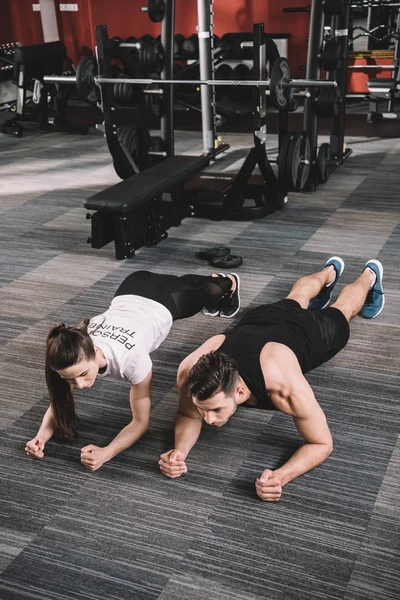 Jovem Treinador Fazendo Exercício Prancha Conjunto Com Desportista — Fotografia de Stock