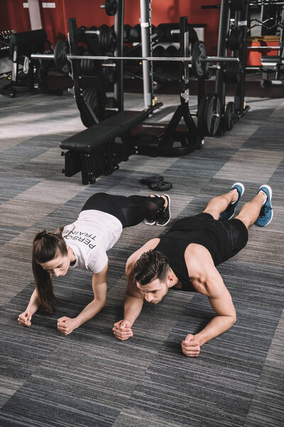young trainer doing plank exercise together with sportsman