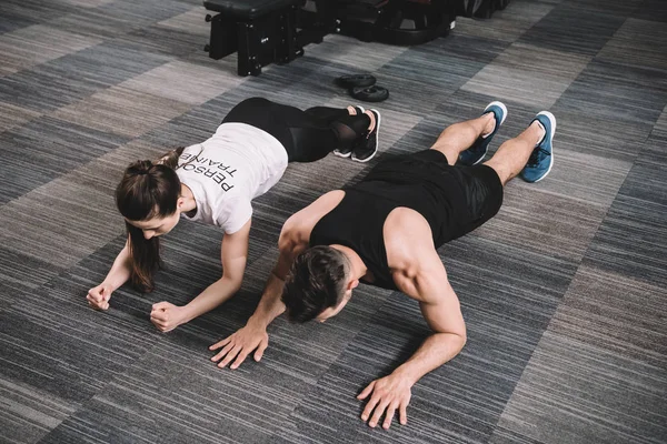 Jovem Treinador Fazendo Exercício Prancha Conjunto Com Desportista — Fotografia de Stock