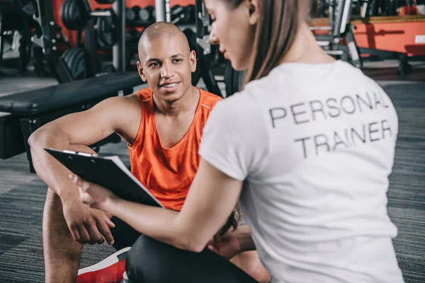 Personal Trainer Showing Clipboard Smiling African American Sportsman Sitting Floor — Stock Photo, Image
