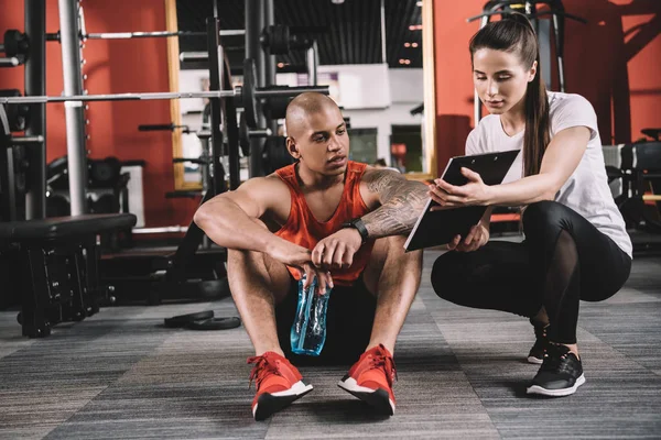 Attractive Trainer Showing Clipboard African American Sportsman Sitting Floor — Stock Photo, Image