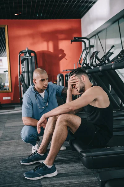 Médico Afroamericano Serio Mirando Joven Deportista Que Sufre Dolor Cabeza —  Fotos de Stock