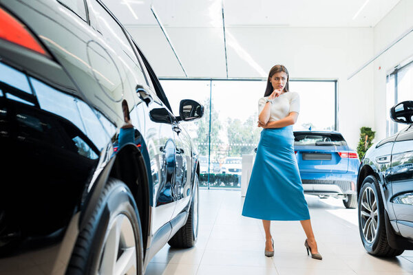 selective focus of pensive woman standing near cars 