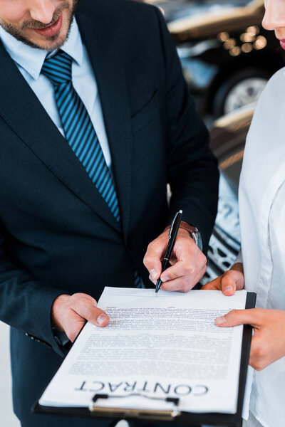 обрезанный вид бородатого мужчины, держащего возле буфера обмена, и женщины в автосалоне
 