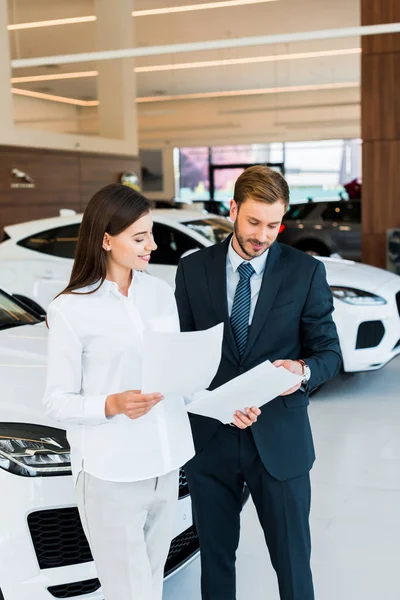 Mulher Alegre Com Homem Barbudo Segurando Papéis Showroom Carro — Fotografia de Stock