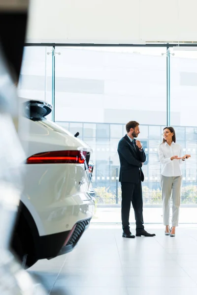 Selektiver Fokus Attraktiver Autohändler Gestikuliert Nahe Bärtigem Mann Autohaus — Stockfoto