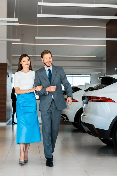 Cheerful Bearded Man Gesturing While Walking Woman Car Showroom — Stock Photo, Image