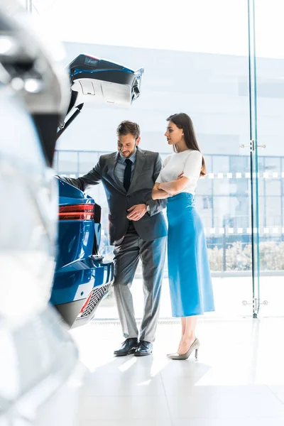 자동차 전시장에서 자동차 트렁크를 여자와 남자의 선택적 — 스톡 사진