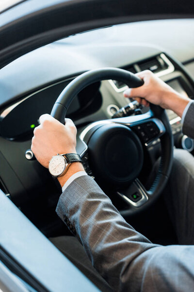 cropped view of man holding steering wheel while sitting in car 