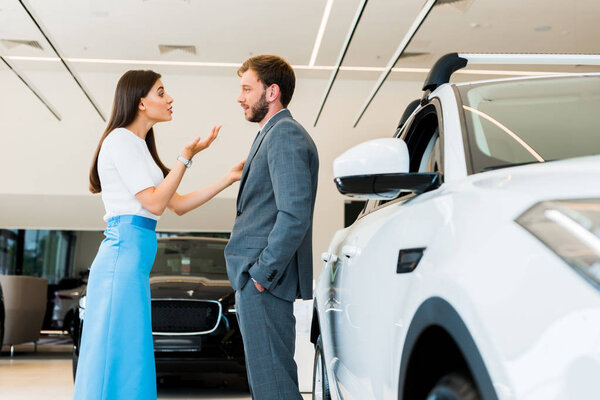 selective focus of attractive woman gesturing while talking with bearded man 