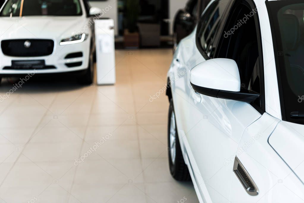 selective focus of white and shiny cars in car showroom 