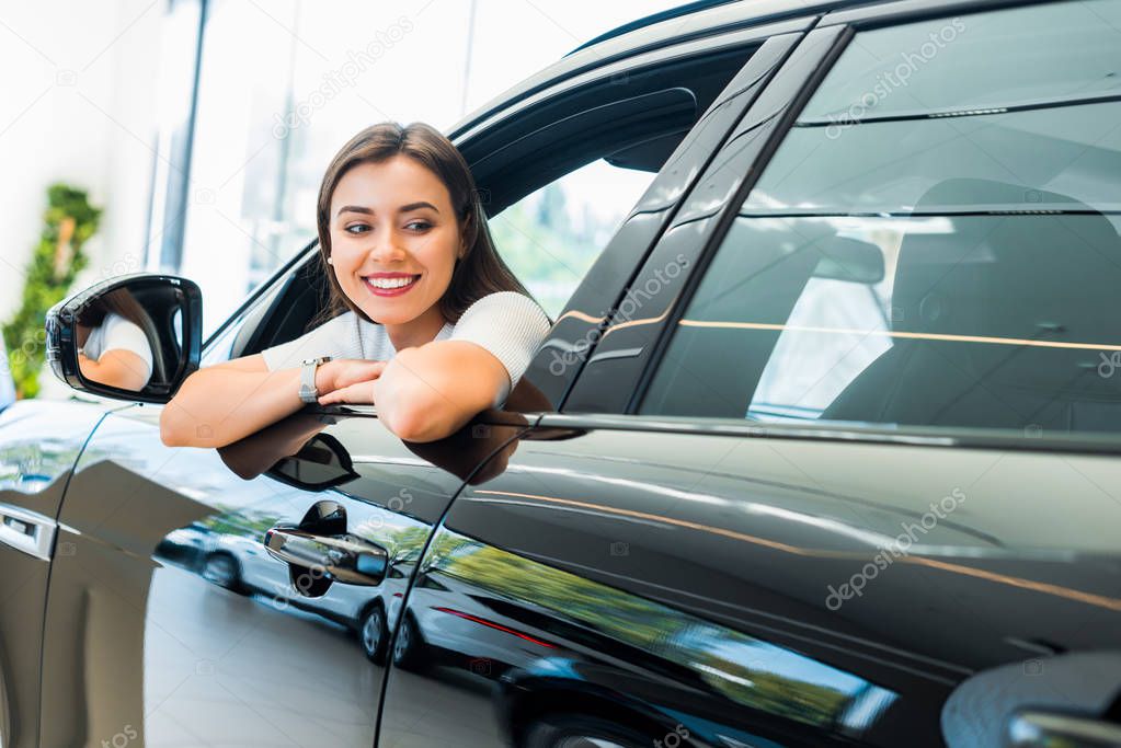 selective focus of cheerful woman sitting in shiny car 