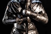 Ausgeschnittene Ansicht eines Ritters in Rüstung mit Schwert isoliert auf schwarz 