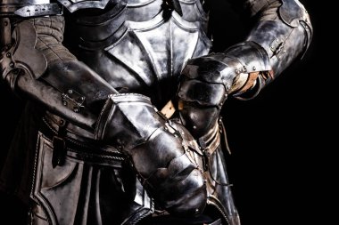 cropped view of knight in armor holding sword isolated on black clipart