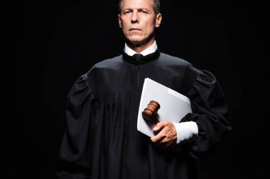 judge in judicial robe holding gavel and papers isolated on black  clipart