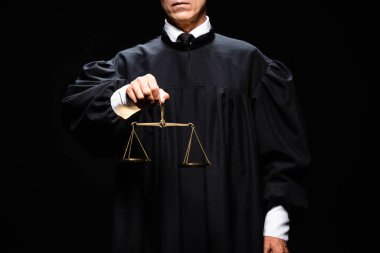 cropped view of judge in judicial robe holding scales of justice isolated on black  clipart