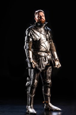 handsome knight in armor looking at camera on black background  clipart