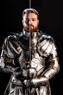 handsome knight in armor holding sword isolated on black clipart