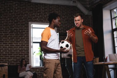 Heyecanlı bir iş adamı Afrika kökenli Amerikalı meslektaşıyla konuşurken el kol hareketi yapıyor.