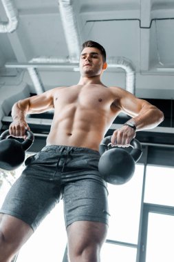 Spor merkezinde ağırlık çalışan yakışıklı ve üstsüz sporcuların düşük açılı görüntüsü