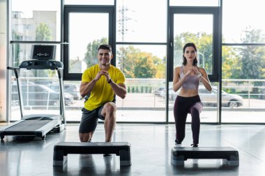 Gülümseyen sporcu ve sporcu kadın spor merkezinde hamle yapıyor.