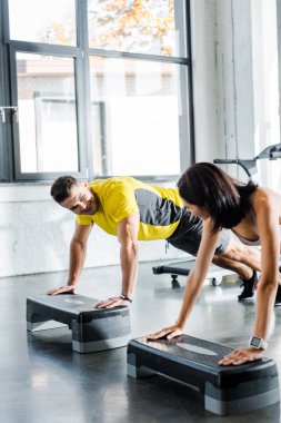 Yakışıklı sporcu ve sporcu kadın spor merkezinde merdiven platformunda tahta yapıyor.