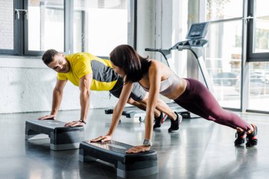 Yakışıklı sporcu ve sporcu kadın spor merkezinde merdiven platformunda tahta yapıyor.