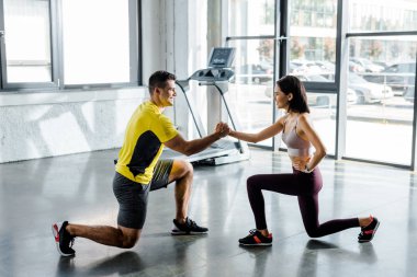 Sporcu ve sporcunun spor merkezinde birlikte hareket edişlerinin yan görüntüsü