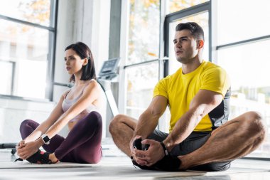 Sporcu ve sporcu kadın spor merkezinde spor minderleri üzerinde geriniyorlar.