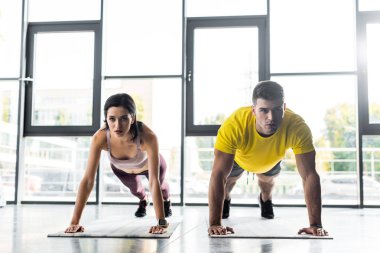 Sporcu ve sporcu kadın spor merkezindeki spor paspaslarda kalas yapıyor.