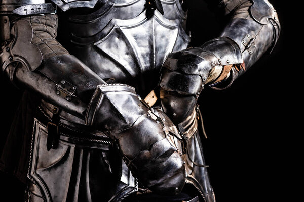 Cropped view of knight in armor holding sword isolated on black