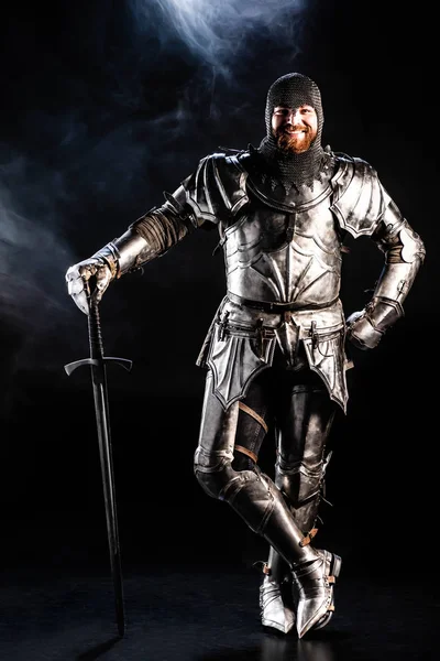 Smiling Knight Armor Looking Camera Holding Sword Black Background — Stock Photo, Image