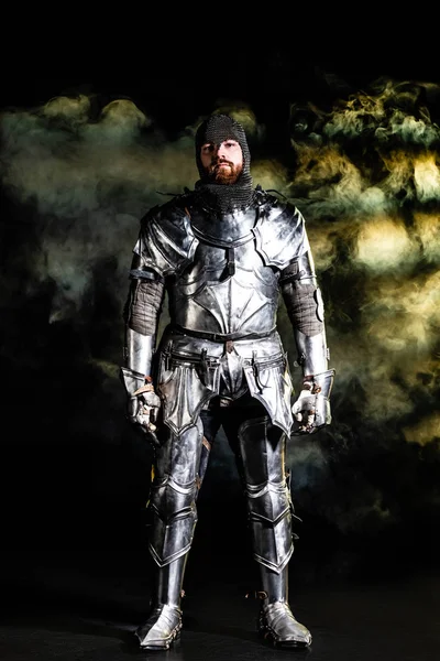 黒を背景にカメラを見る鎧姿のハンサムな騎士 — ストック写真