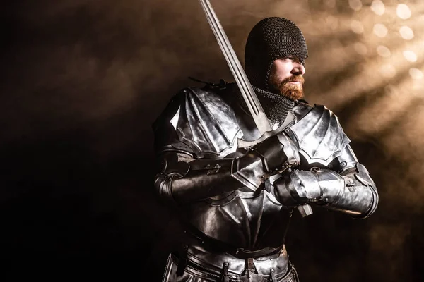 身穿盔甲的英俊骑士手持黑色背景的剑 — 图库照片