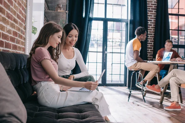 Jonge Zakenvrouwen Kijken Laptop Terwijl Zitten Bank Buurt Van Multiculturele — Stockfoto