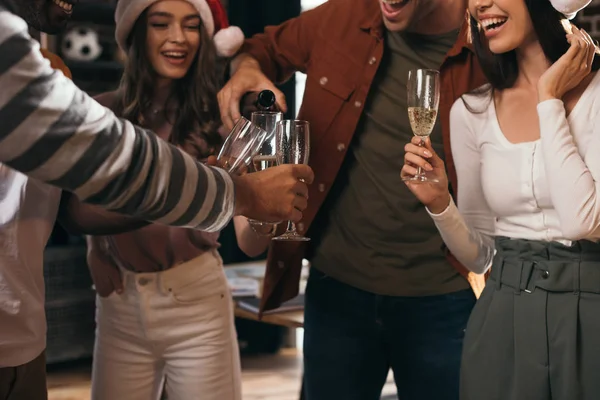 Частичный Взгляд Бизнесмена Наливающего Шампанское Бокалы Счастливых Коллег Шляпах Санты — стоковое фото