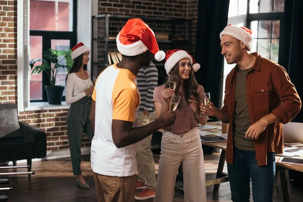 Empresários Multiculturais Felizes Chapéus Santa Falando Enquanto Segurando Copos Champanhe — Fotografia de Stock