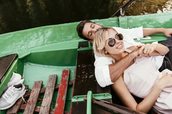 Attractive girl in sunglasses smiling at camera while lying in boat near boyfriend — Stock Image Attractive Girl Sunglasses Smiling Camera While Lying Boat Boyfriend Stock Image