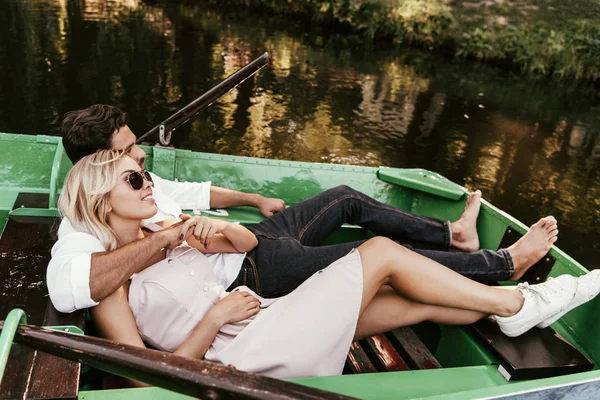 Happy young couple relaxing while lying in boat on lake — Stock Image Happy Young Couple Relaxing While Lying Boat Lake Royalty Free Stock Photos
