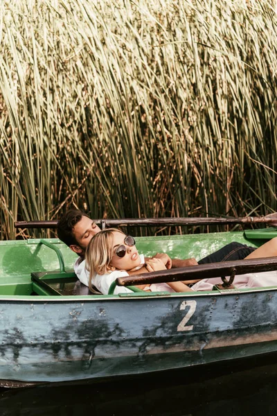 Young couple relaxing in boat on river near thicket of sedge — Stock Image Young Couple Relaxing Boat River Thicket Sedge Stock Image