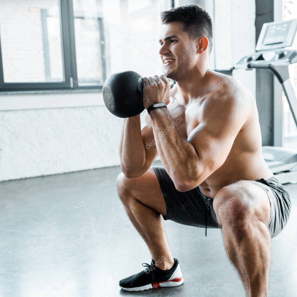 handsome and shirtless sportsman squatting with weight in sports center