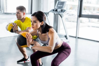 Sporcu ve sporcu kadın spor merkezinde toplarla hiç bir şey yapmıyorlar.